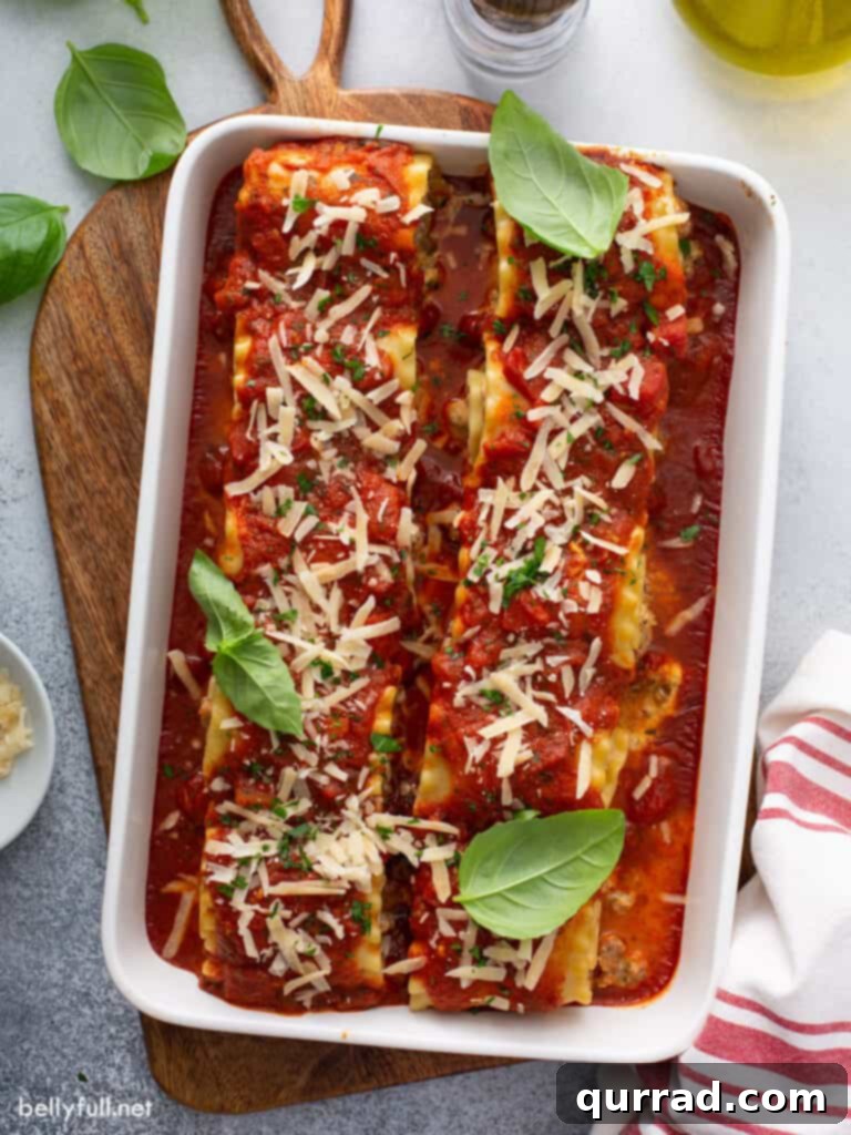 Overhead shot of freshly baked sausage lasagna rolls in a white casserole dish, garnished with fresh parsley