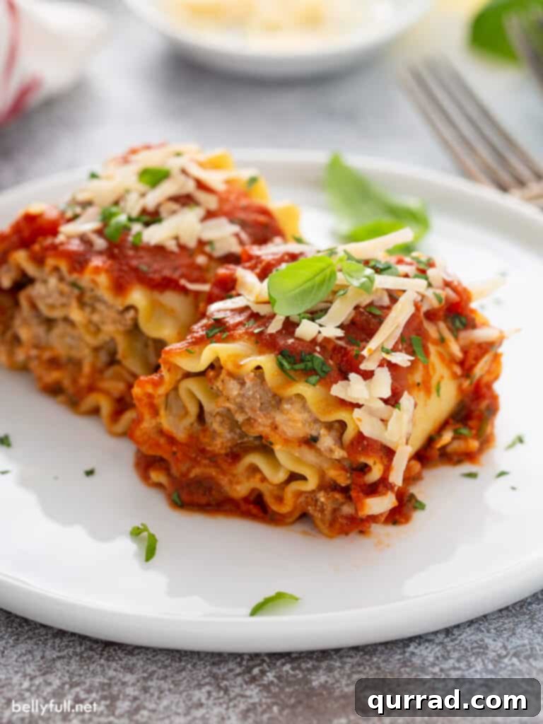 Individual serving of baked sausage lasagna rolls on a white plate, topped with sauce and parsley