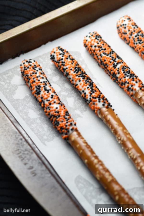 Easy Halloween Pretzel Rods: Sweet, Salty, and Spooktacular! Halloween Pretzel Rods arranged on a baking sheet, showcasing festive sprinkles