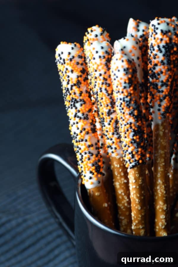 Simple Halloween Pretzel Rods Dipped in White Chocolate Halloween Pretzel Rods standing upright in a mug, showing off their decorated tops
