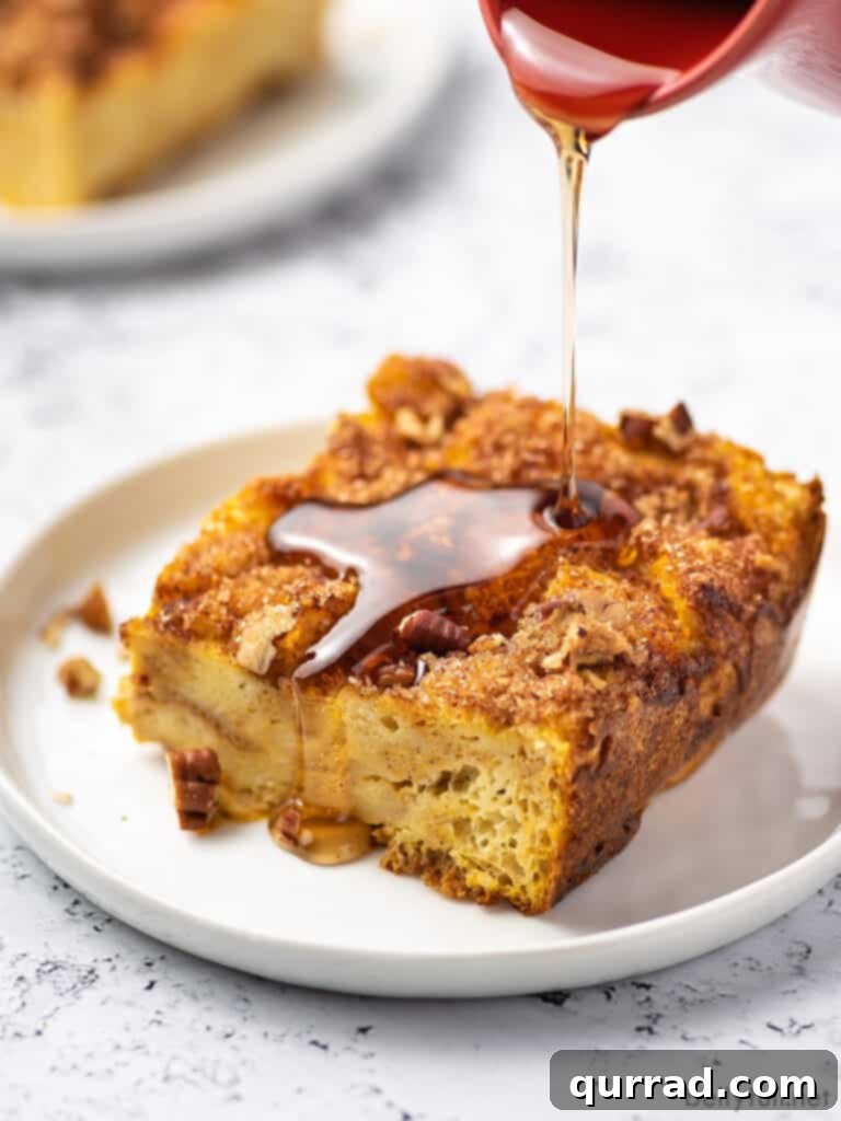 A perfectly golden square of French toast casserole, drizzled generously with maple syrup, highlights the delicious streusel topping and moist interior, ready to be served.