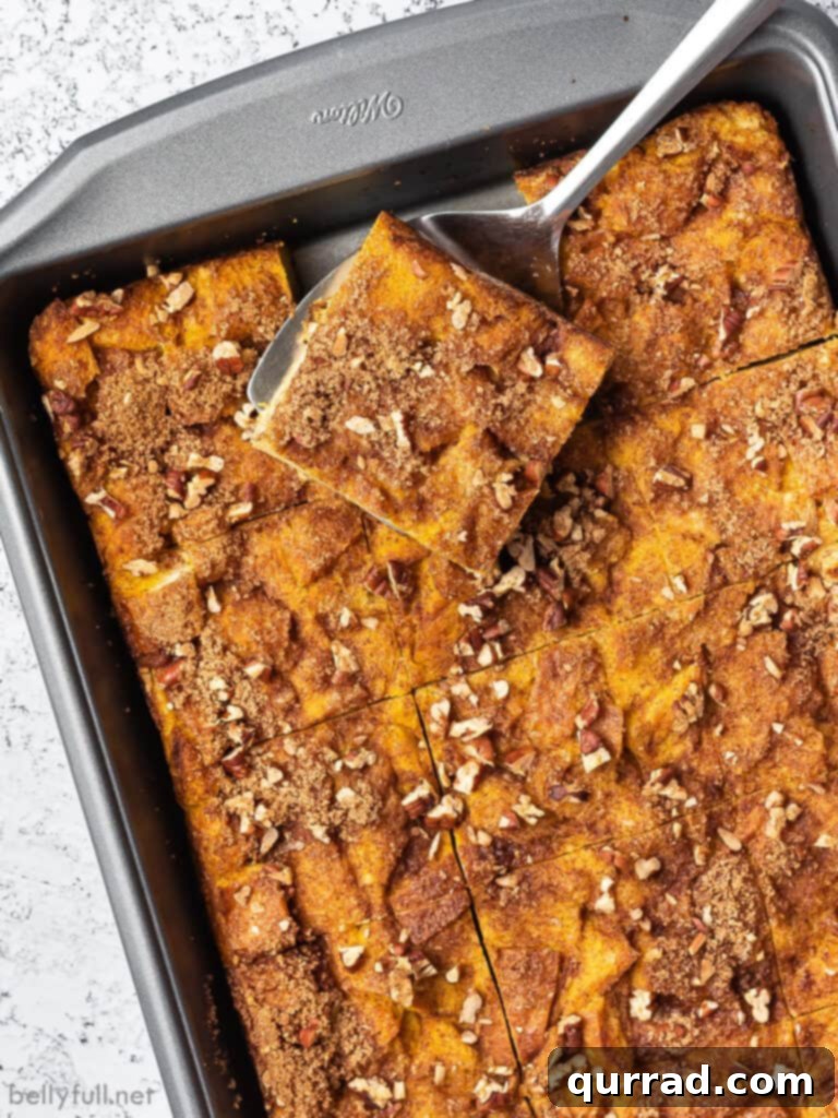 A deep baking dish filled with golden-brown French toast casserole, with a single perfect square lifted on a spatula, showcasing its enticing texture.