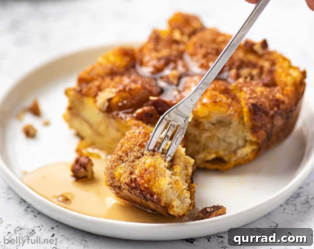 A fork holding a bite-sized piece of French toast casserole, showing the soft, custardy texture and hints of streusel, making it look incredibly appetizing.