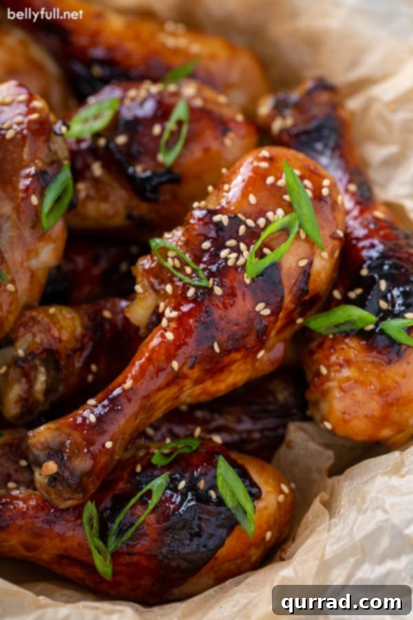Close up picture of Honey Soy Baked Chicken Drumsticks, showcasing a rich, glossy glaze and garnish of sesame seeds and scallions.