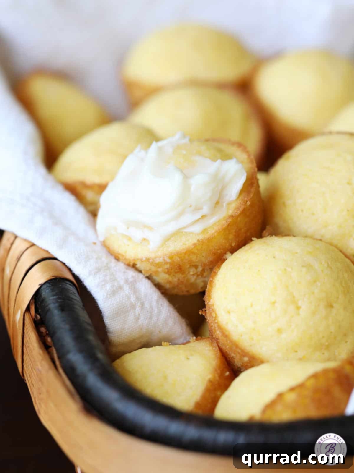Golden Cornbread Bites 3 Close-up of a tender Mini Corn Cake Muffin with a melting swipe of butter on top, highlighting its delicious texture.