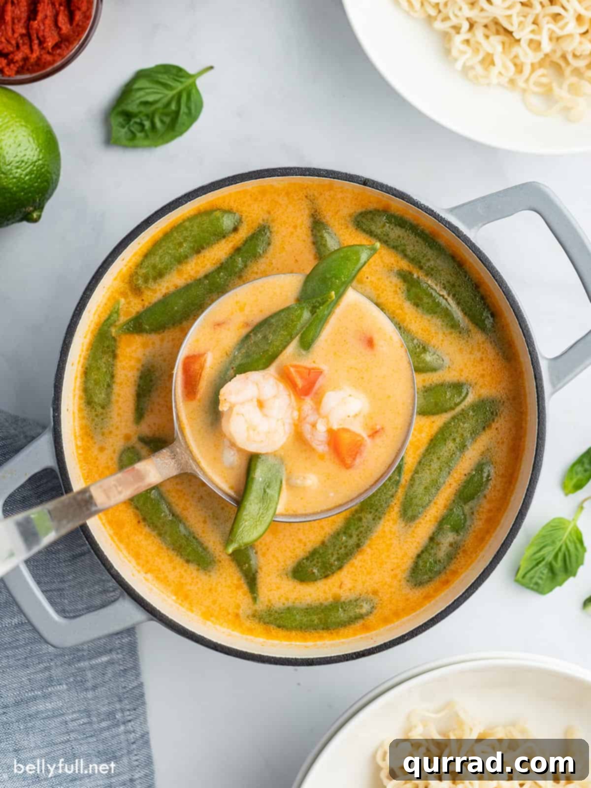 Creamy Thai Coconut Curry Soup 3 Ladle scooping richly colored Thai Curry Soup from a large pot, with visible shrimp, noodles, and vegetables.