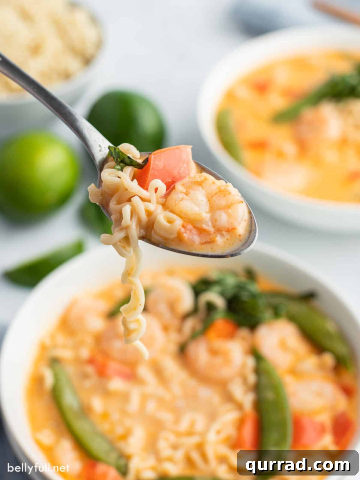 Creamy Thai Coconut Curry Soup 4 Close-up of a spoonful of creamy Thai Coconut Curry Soup, showcasing vibrant noodles, shrimp, and crisp vegetables.