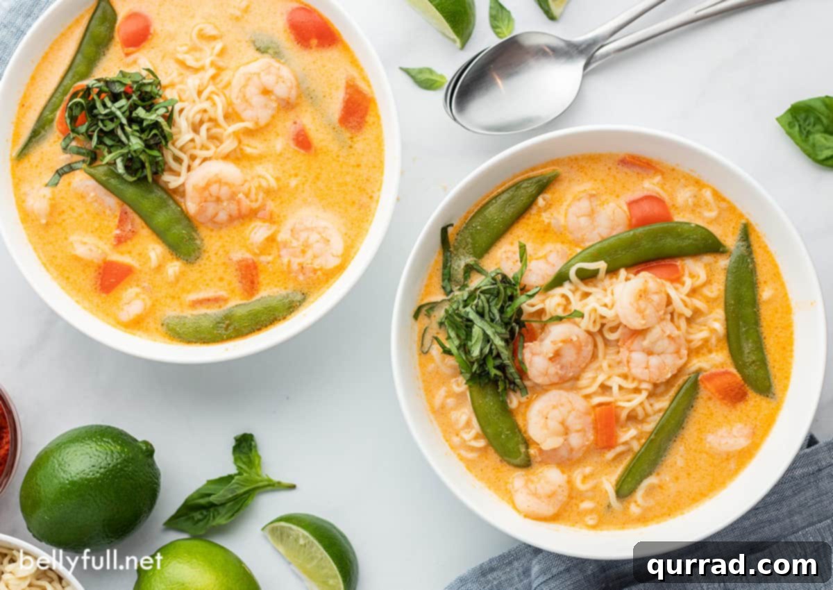 Creamy Thai Coconut Curry Soup 5 Two white bowls filled with Thai Curry Soup, garnished with fresh basil, arranged on a rustic wooden surface.
