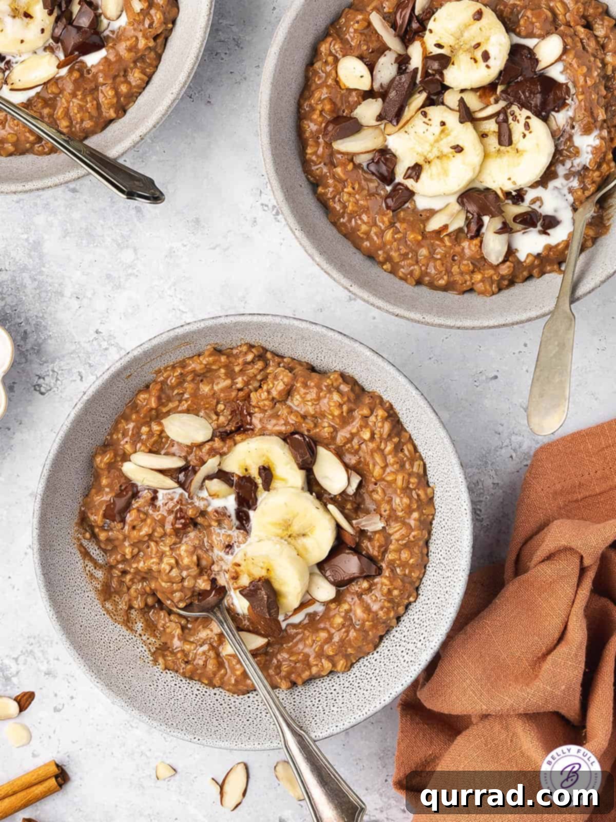 Cocoa-Almond Steel Cut Oatmeal Two bowls of chocolate steel cut oats, garnished with banana slices and almonds.