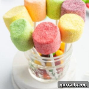 pink, green, yellow, and purple marshmallow pops standing in glass dish