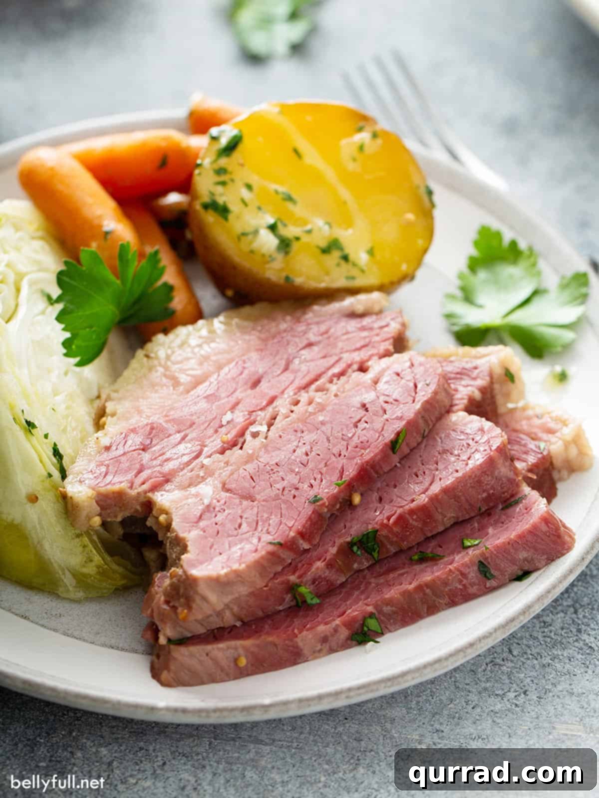3 stacked slices of corned beef on white plate with vegetables