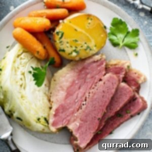 overhead 3 slices corned beef with vegetables on white plate