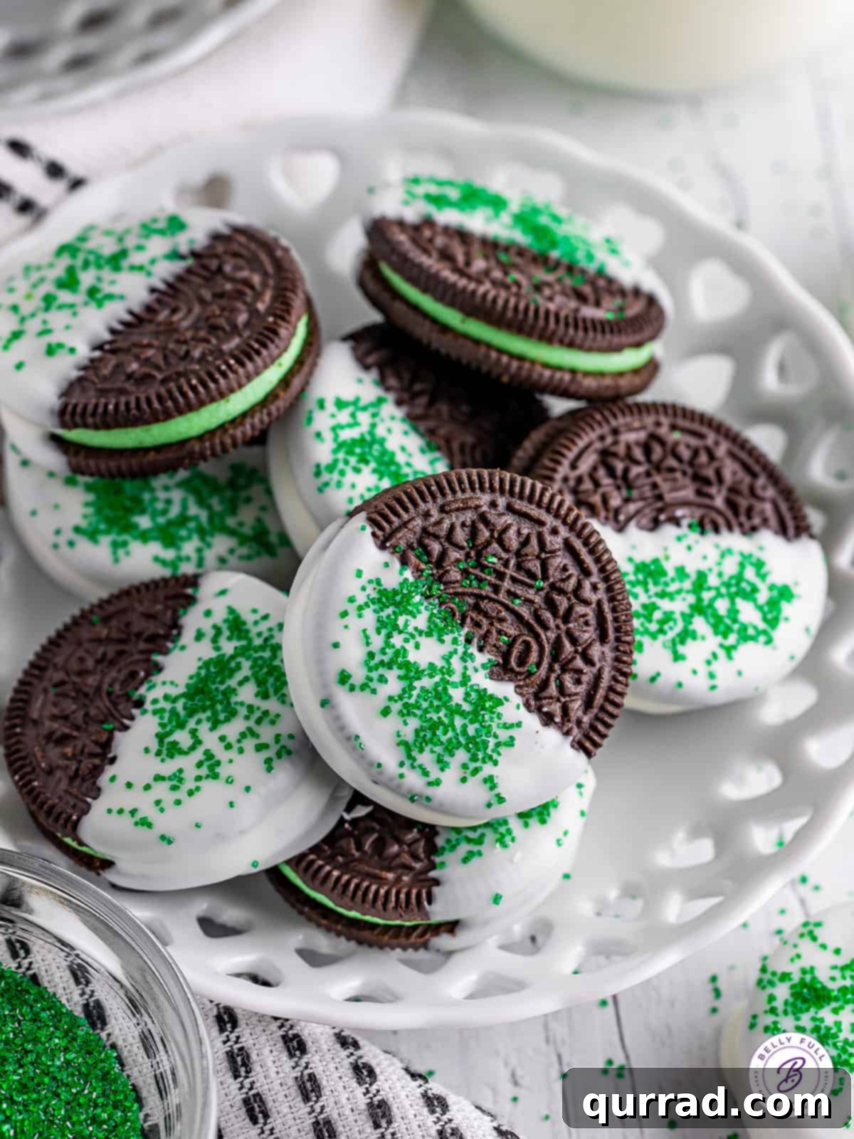 A generous pile of homemade white chocolate-covered mint Oreos, generously sprinkled with green sanding sugar.
