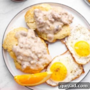 A top-down view of two freshly baked drop biscuits topped with a generous serving of savory sausage gravy, ready to eat.