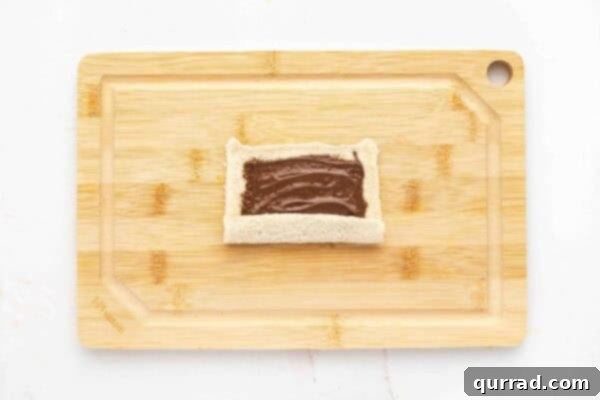 flattened sandwich bread with nutella spread being rolled up
