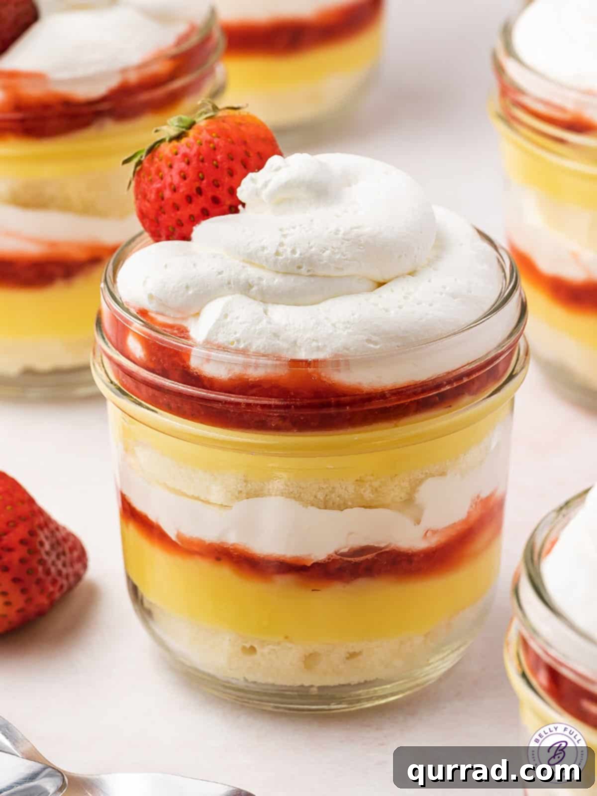 Strawberry Shortcake Layers of Sweetness 2 Individual strawberry shortcake parfait in a glass jar, topped generously with whipped cream and a fresh strawberry slice