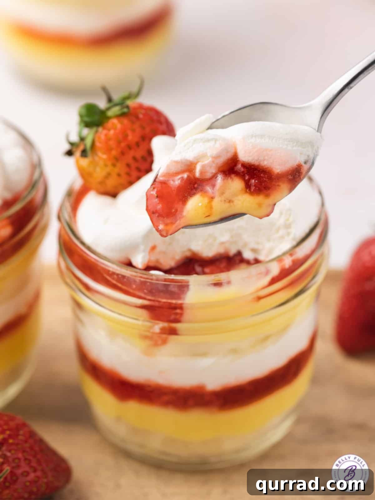 Strawberry Shortcake Layers of Sweetness 4 Close-up of a spoon layered with strawberry sauce, vanilla pudding, and whipped cream, showing the delicious textures
