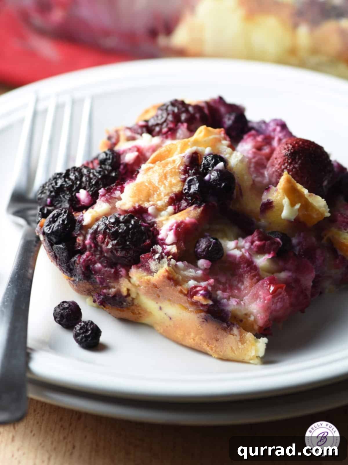 This Breakfast Croissant Puff is an easy and delicious breakfast or dessert casserole using buttery croissants, a cream cheese mixture, and fruit of your choice! Croissant bread pudding on a plate with a fork.