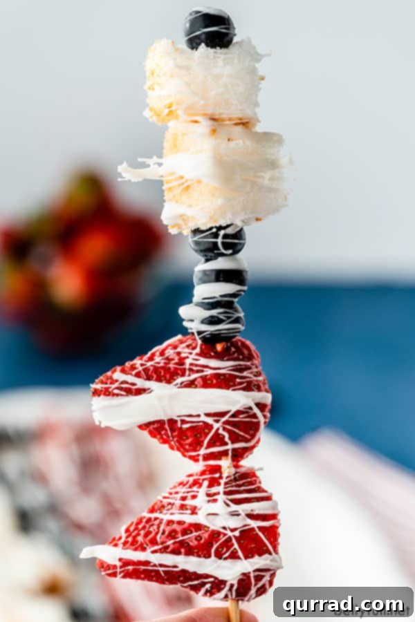 Effortless Fruit Dessert Skewers 3 upright dessert kabob with strawberries, blueberries, angel food cake, and melted white chocolate