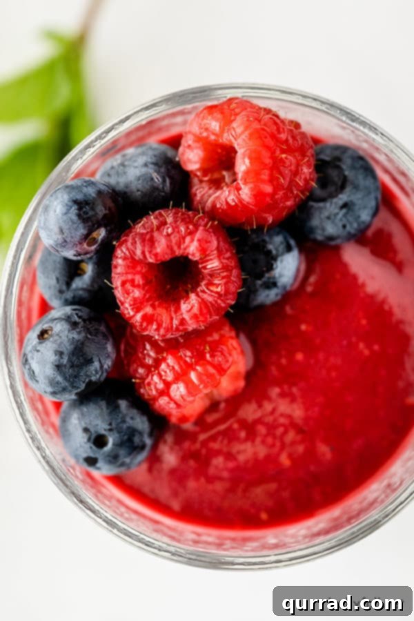 overhead picture of fresh raspberries and blueberries on top of slushie in glass