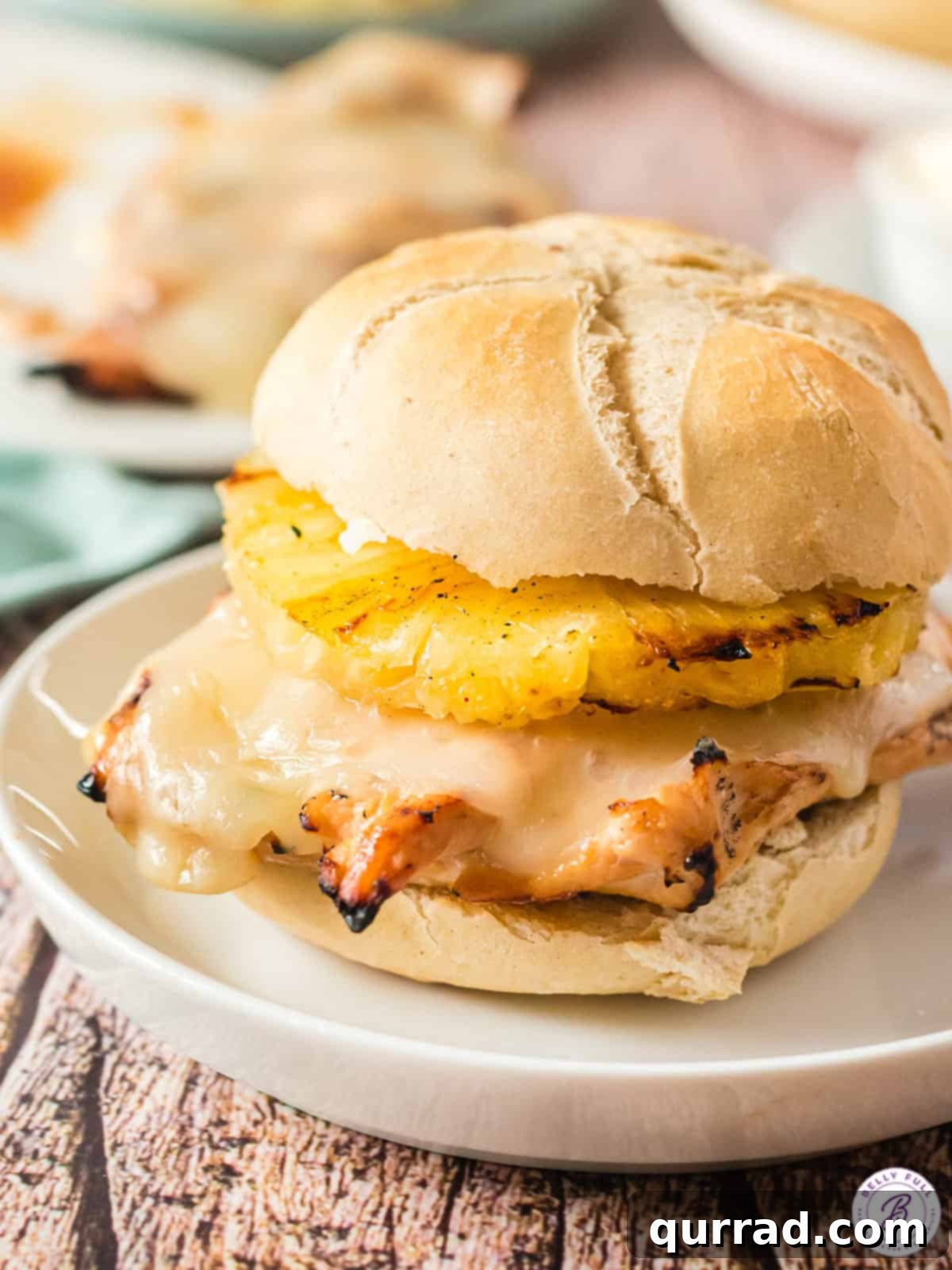 Aloha Grilled Chicken Stack 2 Sweet and tangy grilled Hawaiian chicken sandwich with pineapple and melted cheese on a white plate