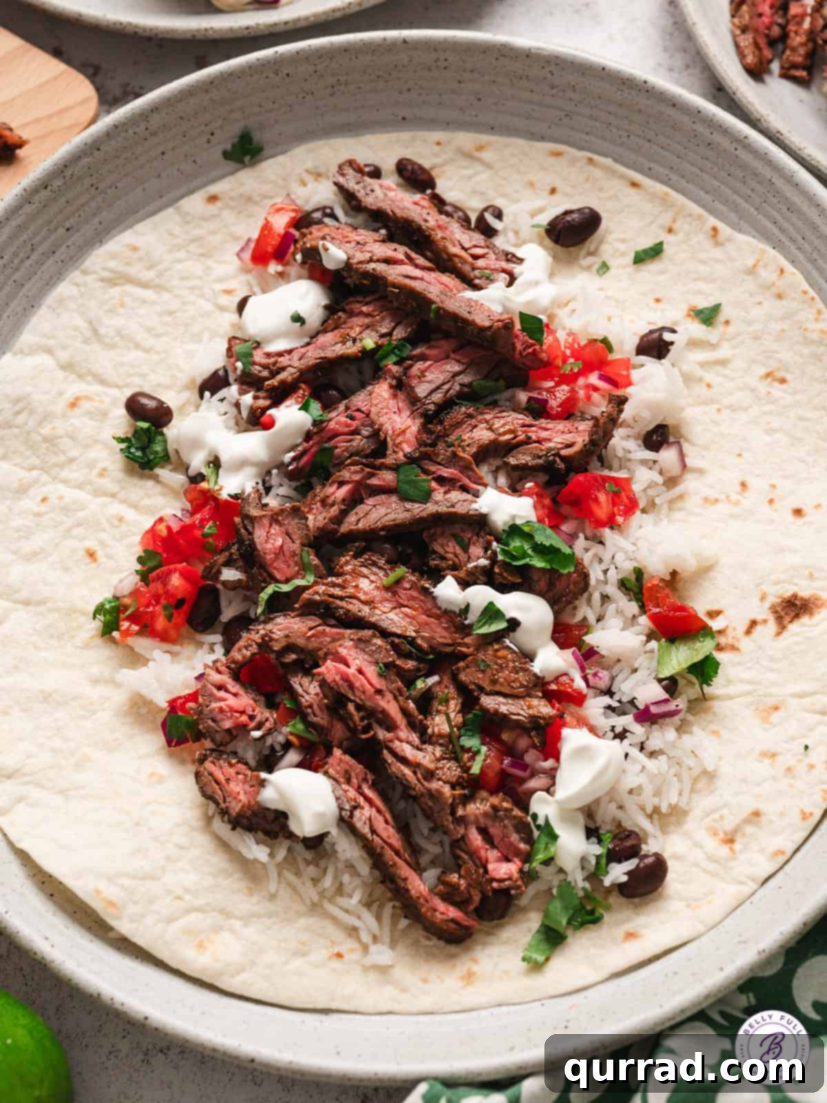 Restaurant-Quality Chipotle Steak Burrito at Home 3 sliced grilled steak, pico de gallo, rice, and sour cream on flour tortilla