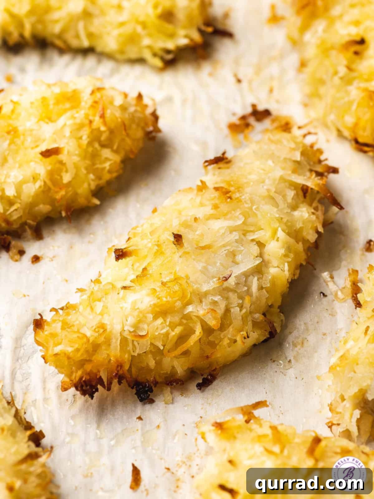 Coconut Crusted Baked Chicken Tenders 3 coconut baked chicken tender on parchment paper