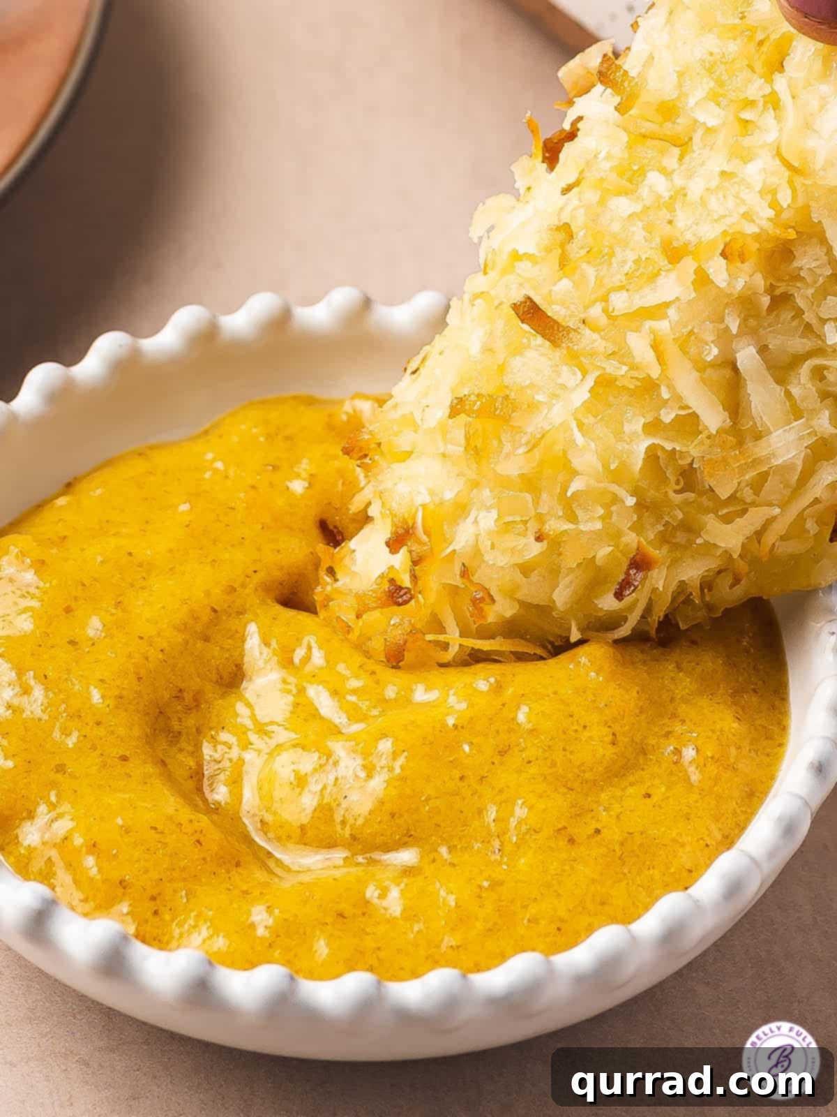Coconut Crusted Baked Chicken Tenders 5 chicken tender being dunked in mustard sauce