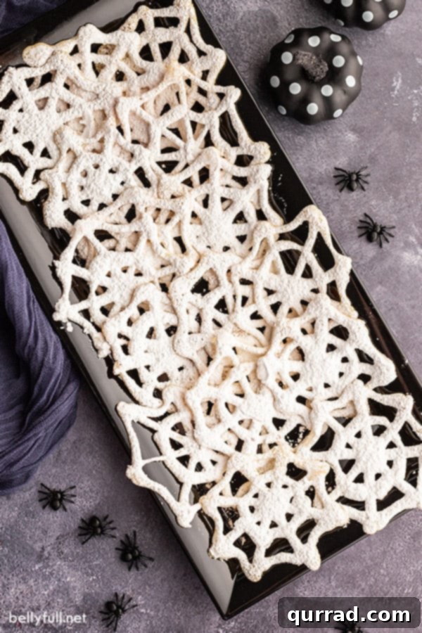 Spooky Spiderweb Delights 4 An artistic overhead arrangement of spiderweb Halloween cookies filling a black serving tray, beautifully dusted with powdered sugar.