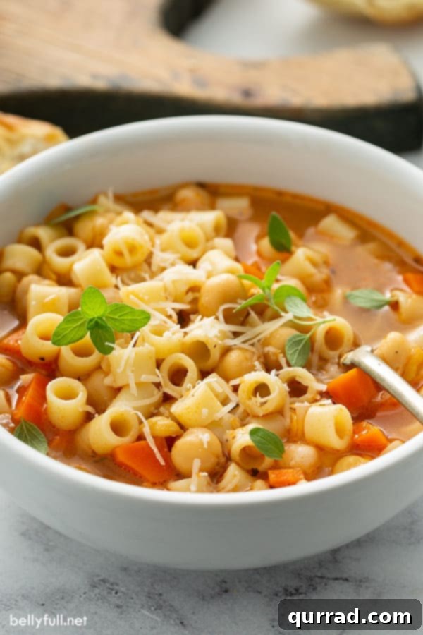 Hearty Pasta and Chickpea Stew 4 Close-up of Pasta e Ceci served in a white bowl with a spoon, ready to be enjoyed.