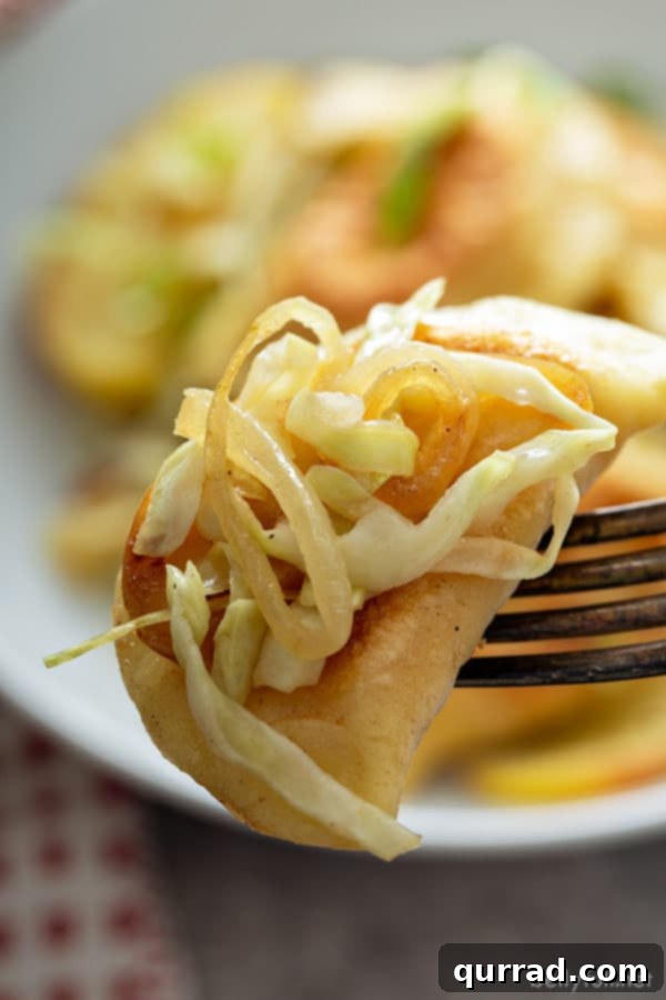 A single pan-fried pierogi perfectly impaled on a fork, showcasing its golden exterior, with a background of tender sautéed onions and cabbage, ready to be enjoyed.