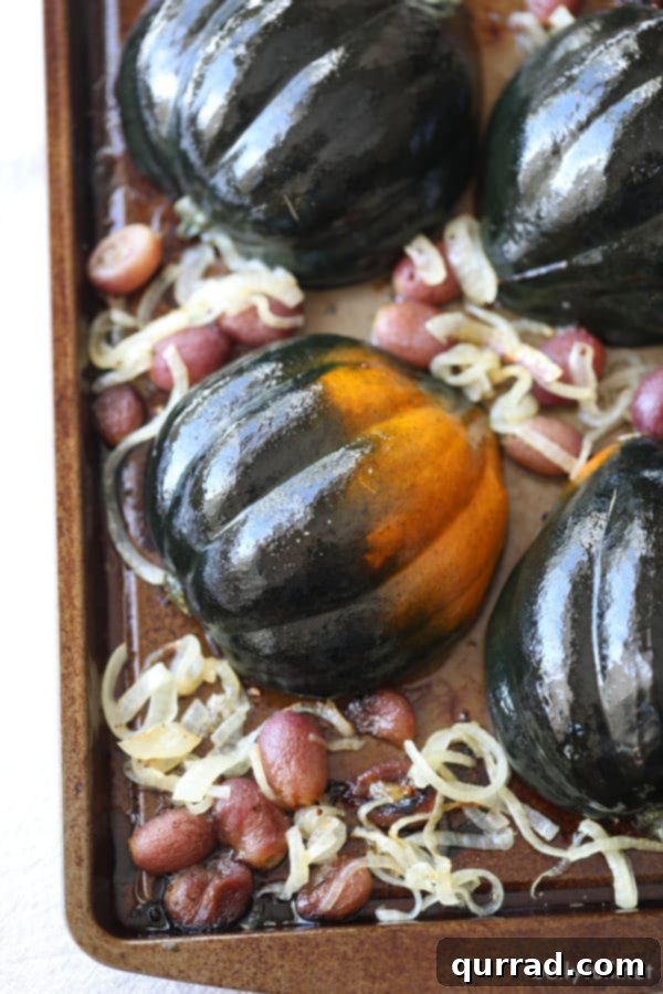 This Stuffed Acorn Squash has that wow factor! Filled with grains, roasted grapes, and caramelized onions, it's a flavor explosion in every bite! #acornsquashrecipes #roastedacornsquash #stuffedacornsquash roasted winter squash halves on a baking sheet
