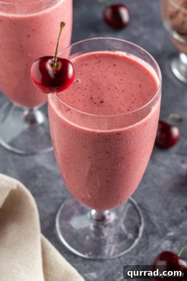 Black Forest Smoothie 4 Overhead shot of a tall glass filled with a decadent cherry smoothie, garnished with a fresh cherry on the rim.