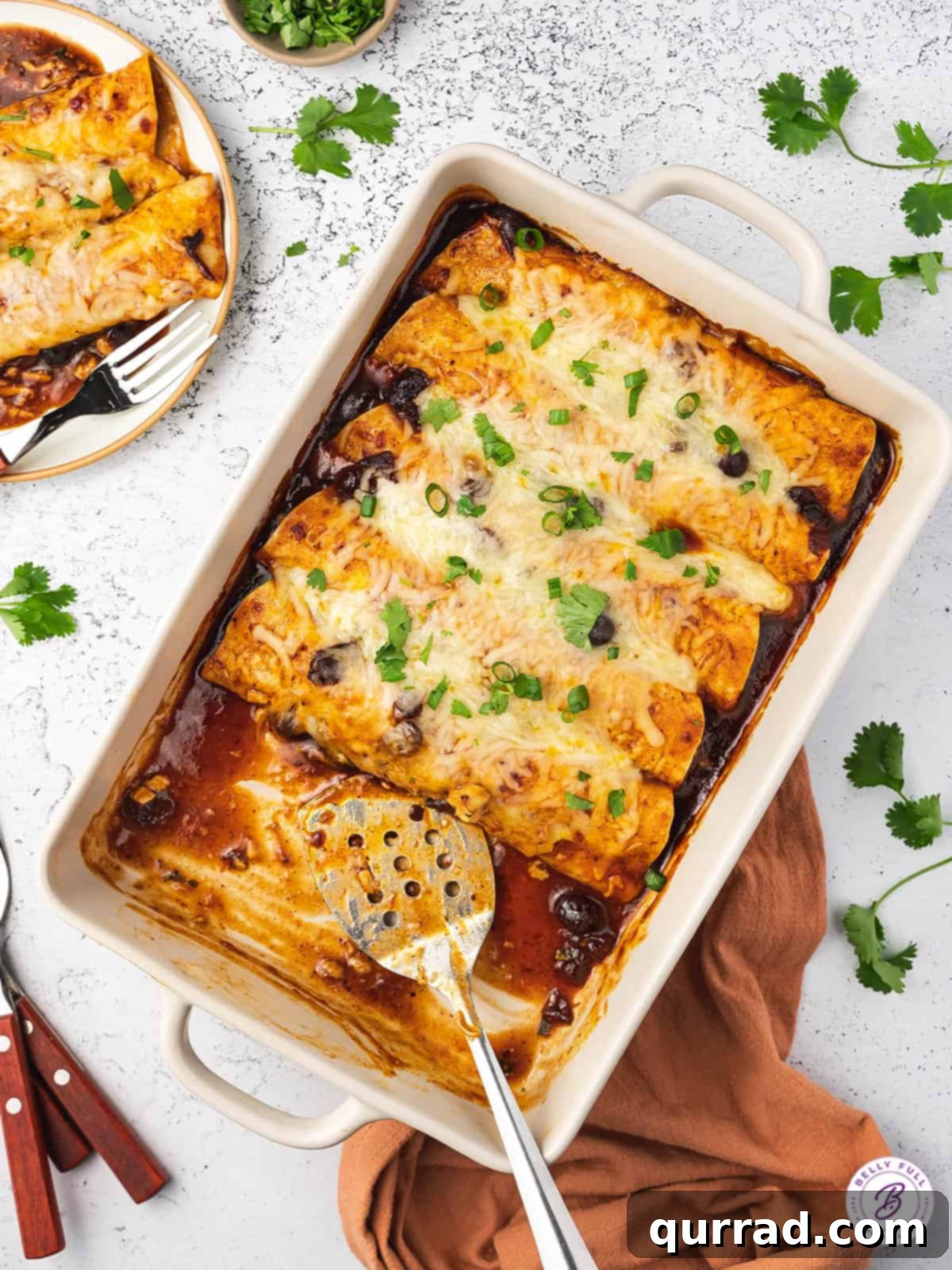 Thanksgiving Leftovers Reinvented 3 Overhead view of vibrant cranberry turkey enchiladas in a baking dish, with a serving spatula ready to dish out a portion.