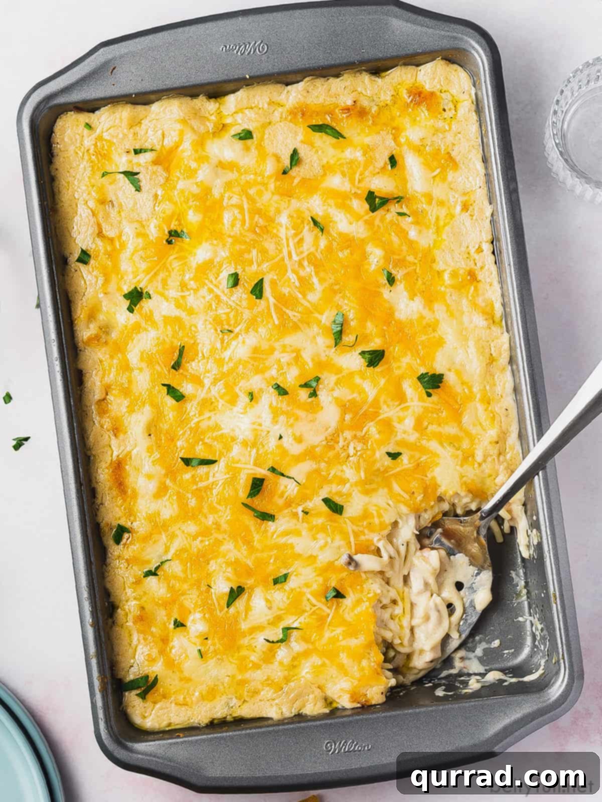 Thanksgiving Leftovers Reinvented 7 A hearty turkey tetrazzini baked to perfection in a casserole dish, with a portion scooped onto a serving spoon, highlighting its creamy, cheesy texture.
