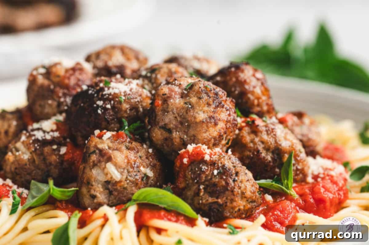 Mouth-watering homemade Italian Meatballs served over a bed of spaghetti with rich tomato sauce.