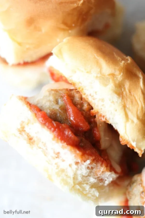 Speedy Meatball Sliders 3 Close-up view of perfectly cooked Italian meatball sliders, showcasing melted cheese and rich marinara sauce.