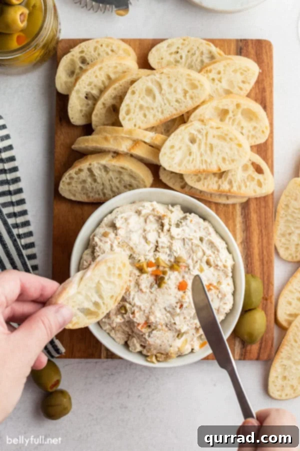 Two-Ingredient Olive Tapenade 3 Hands holding a piece of bread and a knife, reaching into a white bowl of olive dip