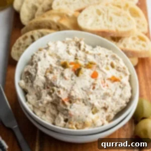 White bowl filled with olive spread and slice bread in the background