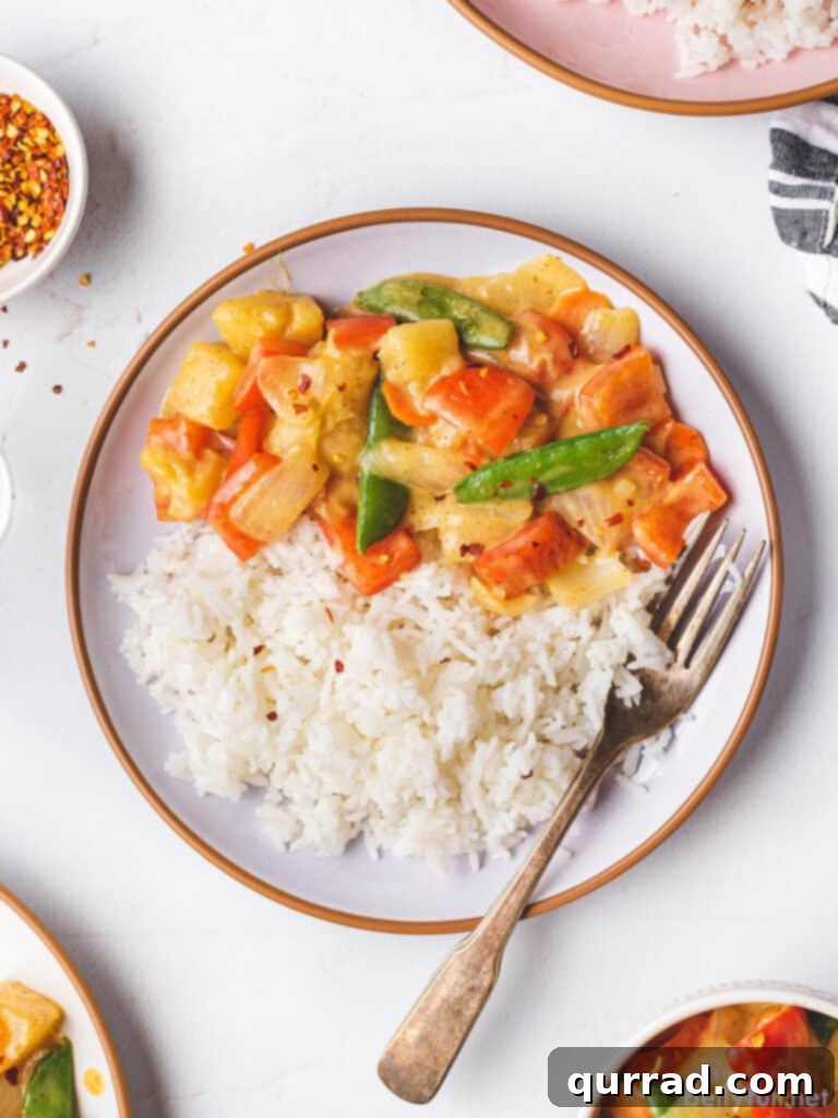 Effortless Veggie Wok 4 Overhead shot of a single plate of coconut curry vegetable stir fry with white rice, garnished with fresh herbs, showcasing a perfectly portioned meal.