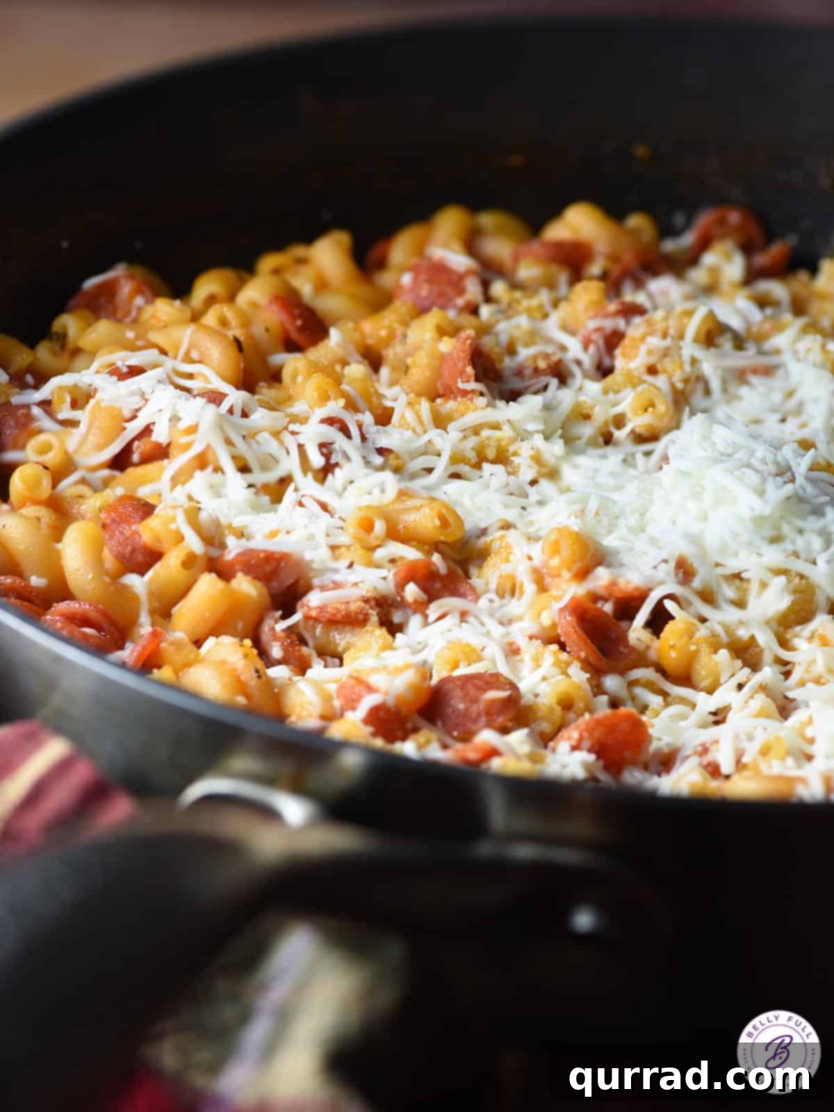 Pizzaroni Mac and Cheese 9 Pepperoni pizza mac and cheese in a large skillet, with fresh parsley and extra cheese sprinkled on top, ready to be served.