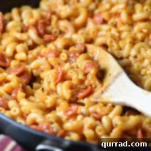 A closer look at a portion of skillet Macaroni and Cheese on a wooden spoon, garnished with fresh herbs.
