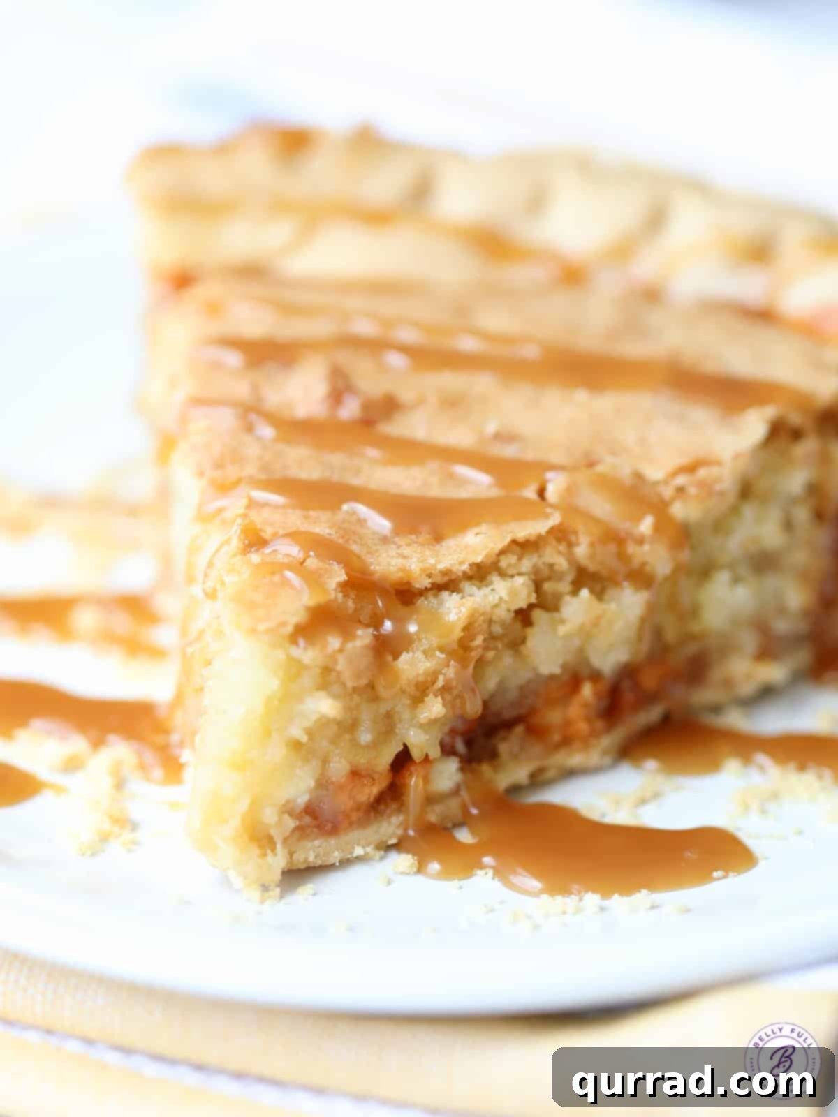 Decadent Macadamia Butterscotch Cookie Pie 2 Close-up slice of golden Macadamia Butterscotch Pie with a caramel drizzle, showcasing its gooey texture and embedded nuts and chocolate chips.