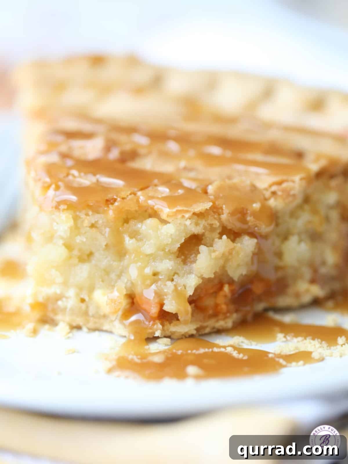 Decadent Macadamia Butterscotch Cookie Pie 4 Close-up view of a slice of Macadamia Butterscotch Pie with a small bite taken out, revealing the gooey interior with melted chocolate and nuts.
