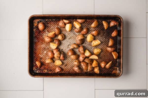 Perfectly roasted golden baby potatoes on a baking sheet, fork-tender.