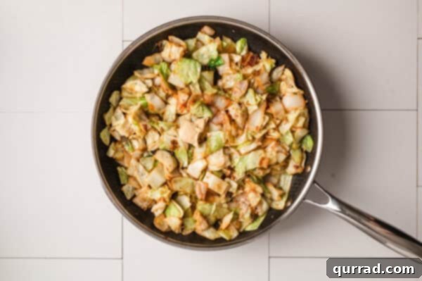 Overhead shot of stir-fried cabbage and onions mixing in a skillet.