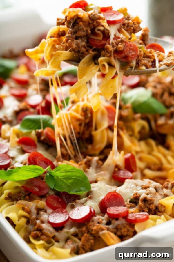 Cheesy Pizza Noodle Bake 5 portion of pizza noodle casserole being lifted out of baking dish with serving spoon