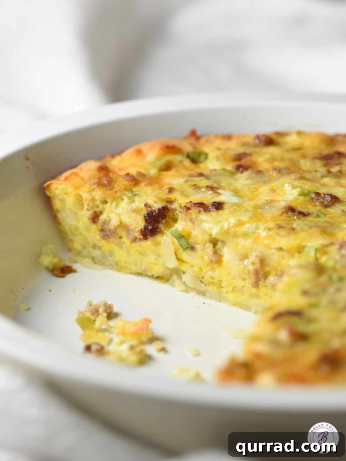 Crispy Hash Brown Quiche 3 A whole hash brown crusted sausage quiche, ready to be sliced, in a ceramic pie plate.