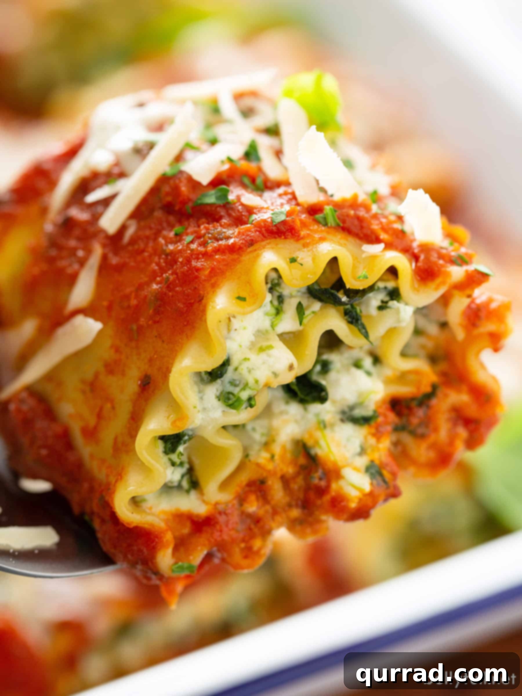 Savory Lasagna Pinwheels 2 Close-up of a golden-baked lasagna roll-up resting on a serving spatula, showcasing melted cheese and rich marinara sauce.