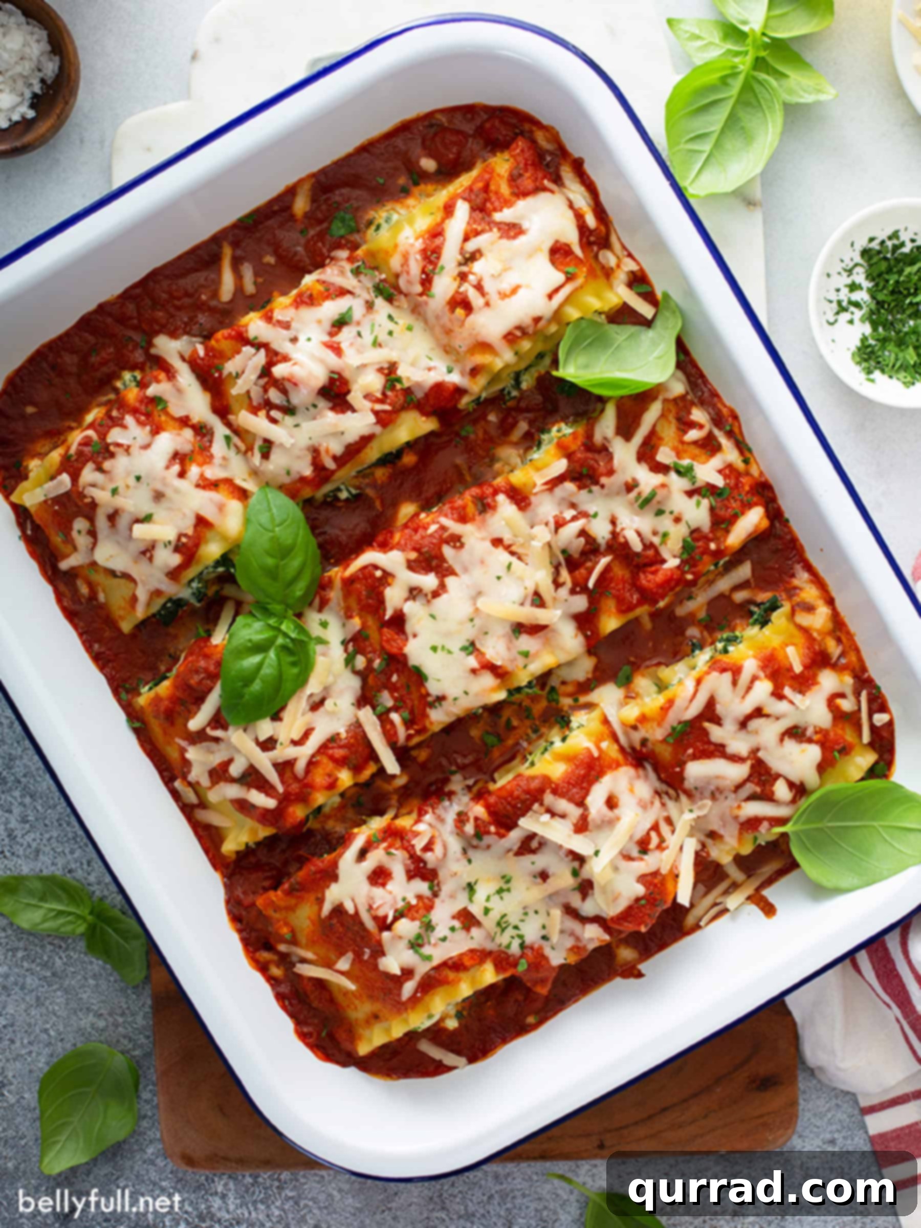 Savory Lasagna Pinwheels 3 Overhead view of nine perfectly arranged lasagna roll-ups baking in a white ceramic dish, covered in marinara and melted mozzarella.